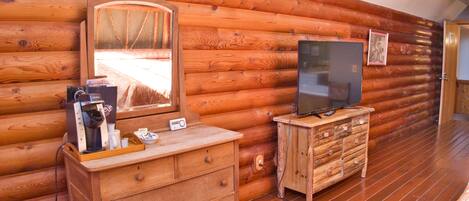 Una habitación tipo cabaña de madera con un aparador, televisor y un espejo grande.