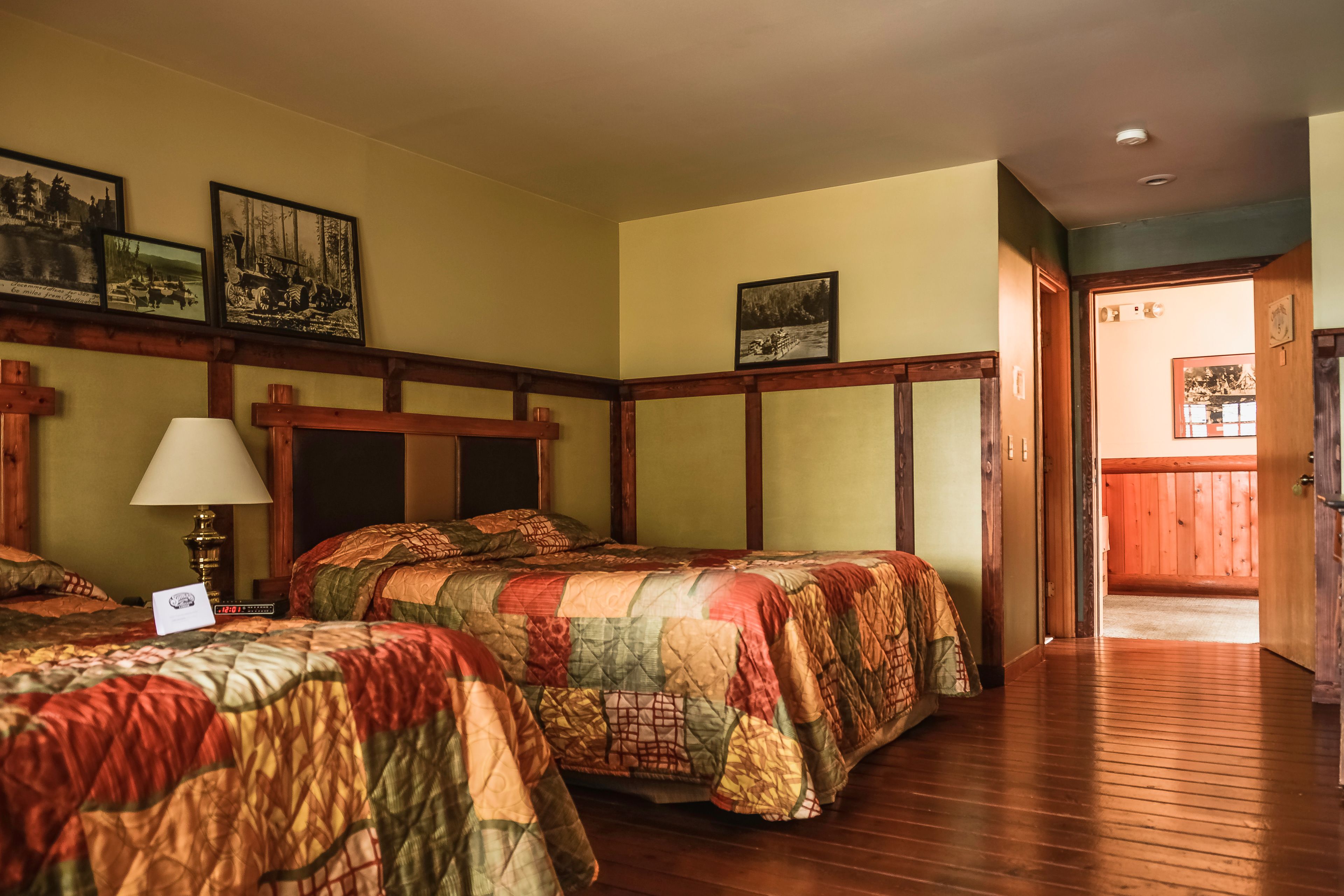 Een hotelkamer met twee bedden, houten vloeren en een houten hoofdeinde.
