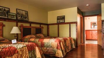 Quarto de hotel com duas camas, piso de madeira e cabeceira de madeira.