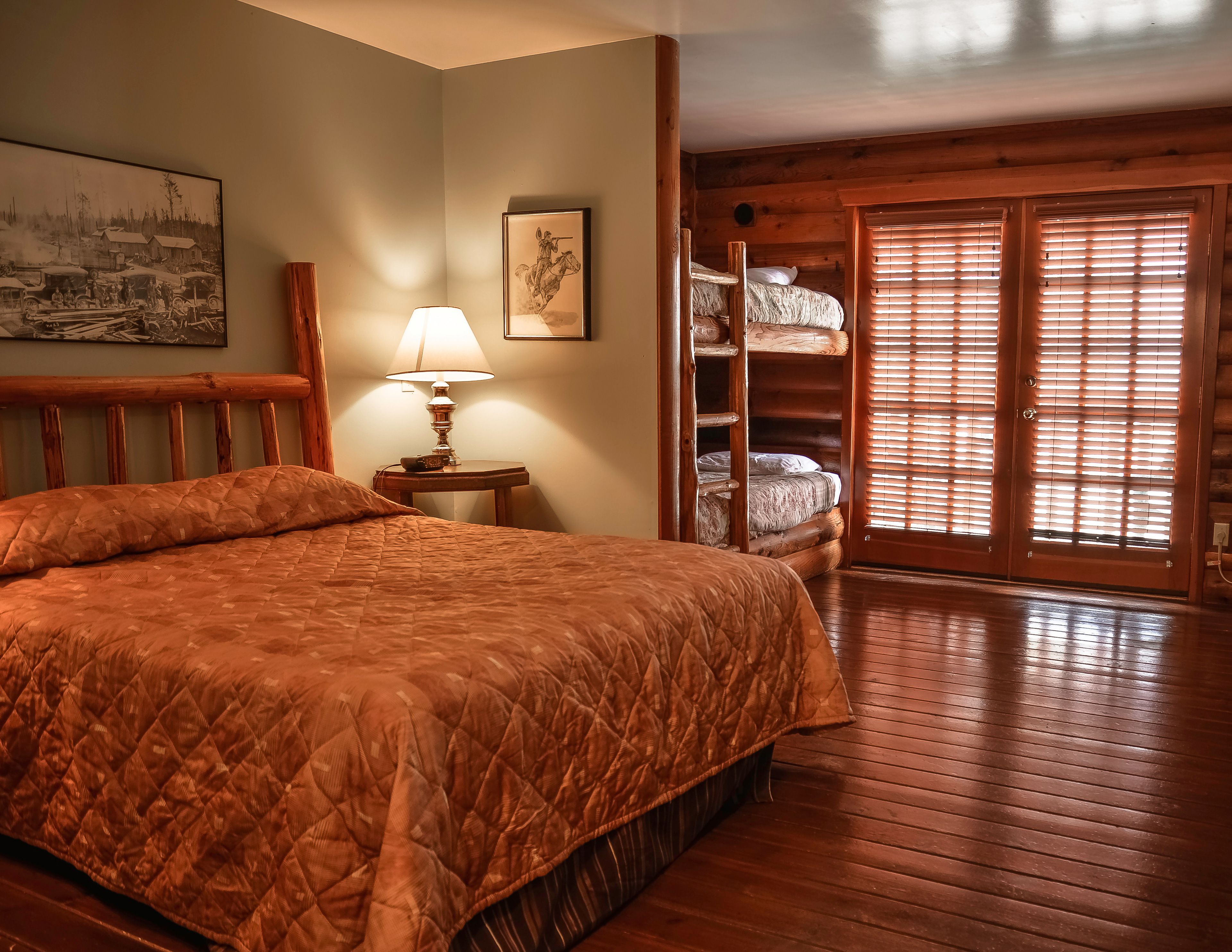 A room with a large bed, a wooden ladder, a lamp, and a picture on the wall.