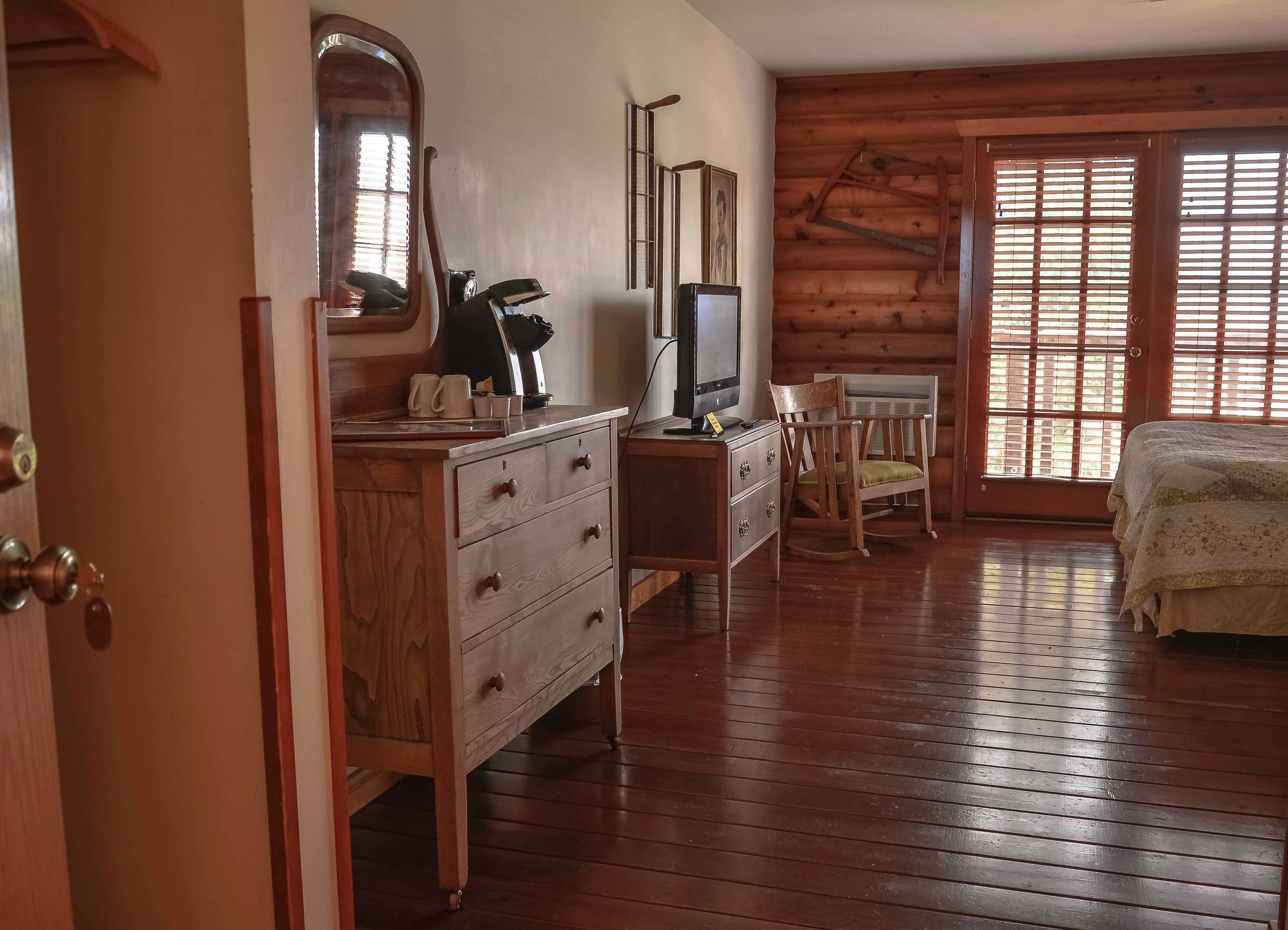 A wooden-paneled room with a wooden dresser, a television, a chair, and a bed.