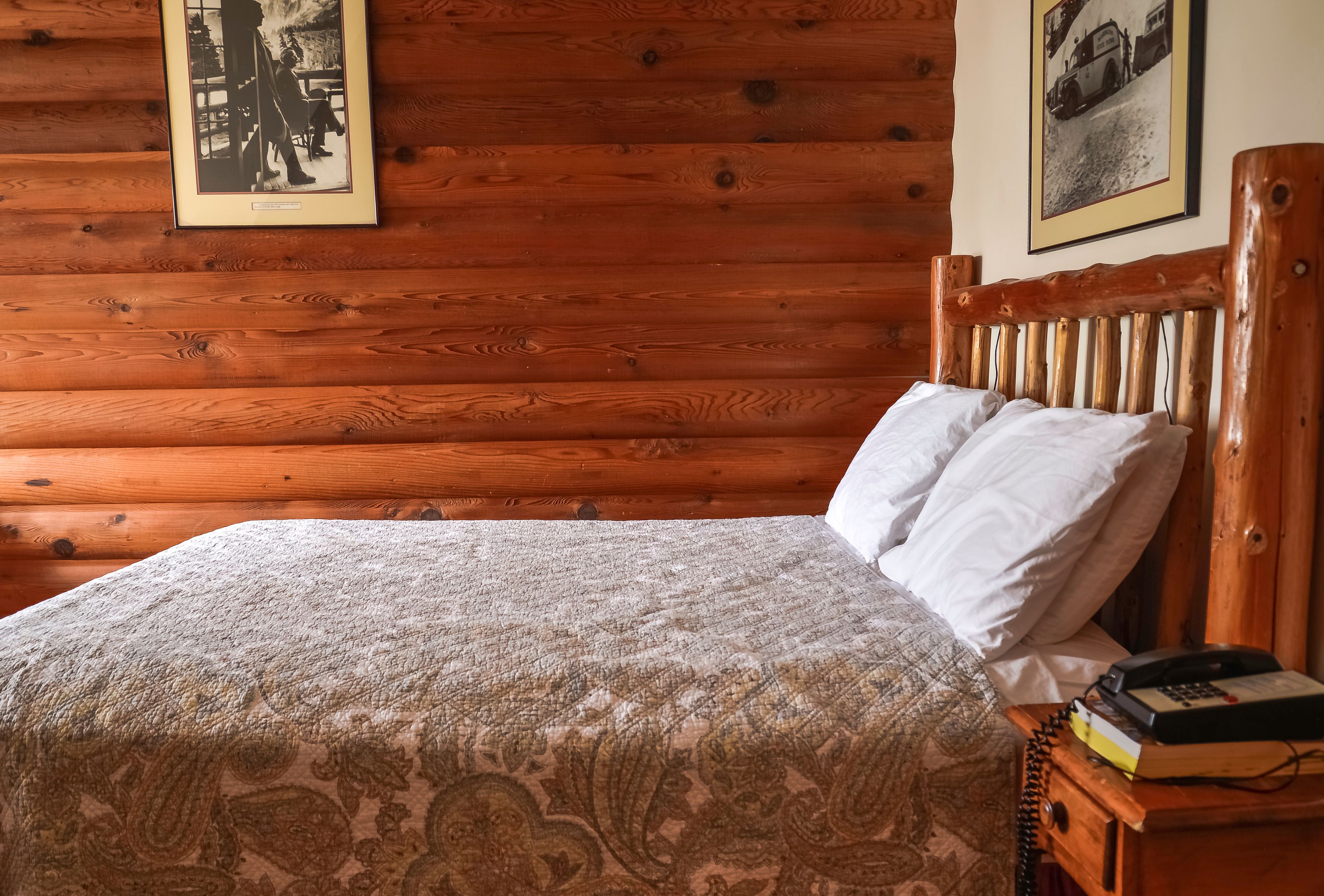 A wooden-paneled room with a bed, a nightstand, and a framed picture on the wall.