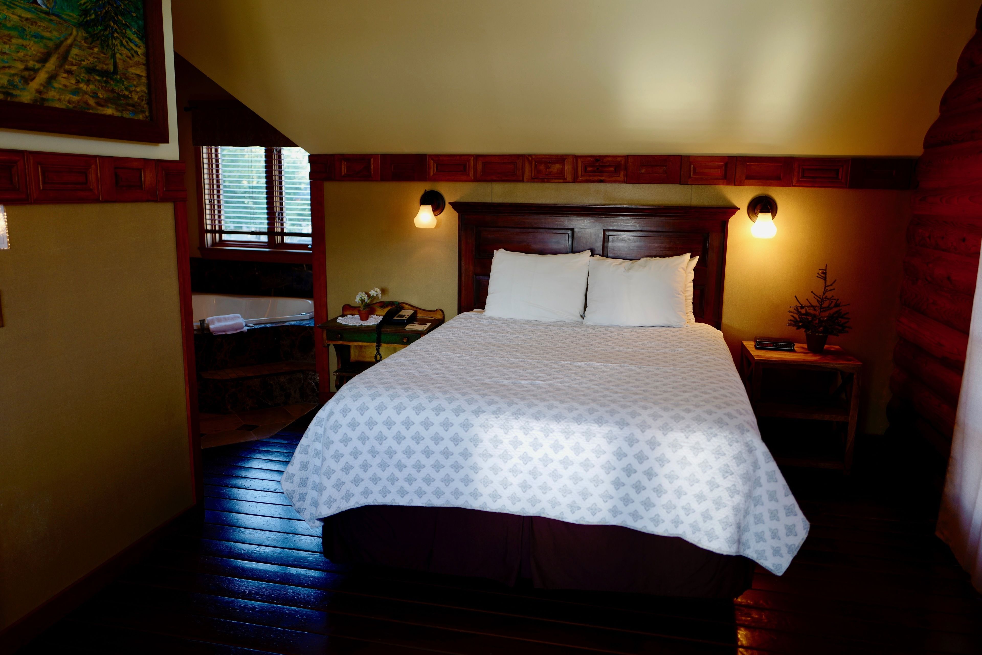 A neatly made bed with a patterned bedspread, wooden headboard, and two bedside lamps.