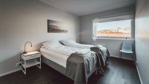 Makuuhuoneessa on kaksi sänkyä, yöpöytä, tuoli ja ikkuna, josta avautuu näkymä maisemaan.