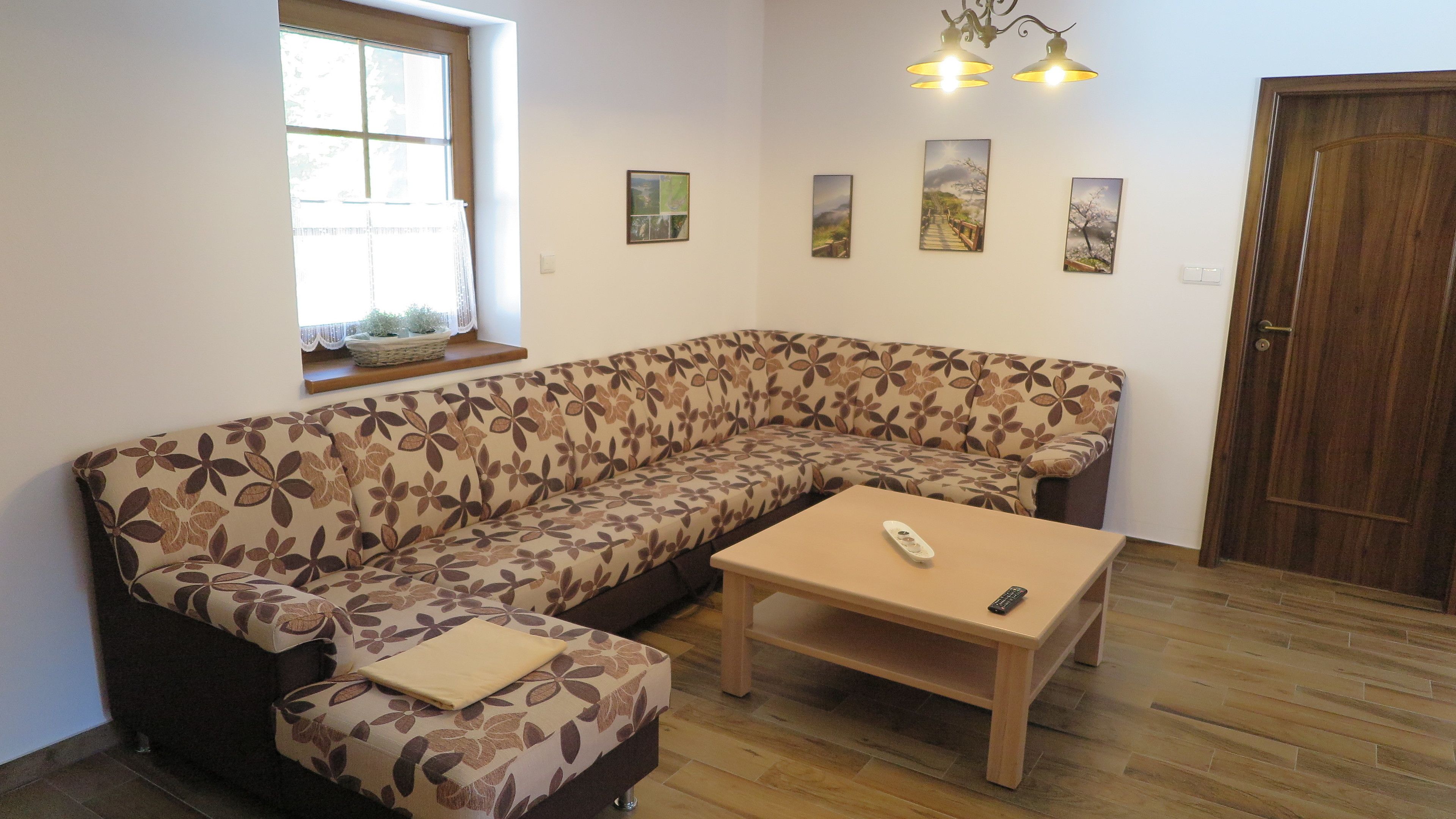 A living room with a floral sofa, a wooden coffee table, and a remote control on it.