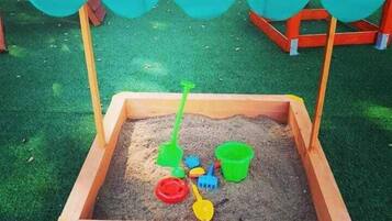 Ein Sandkasten mit Holzränder und einer grünen Plane darüber.