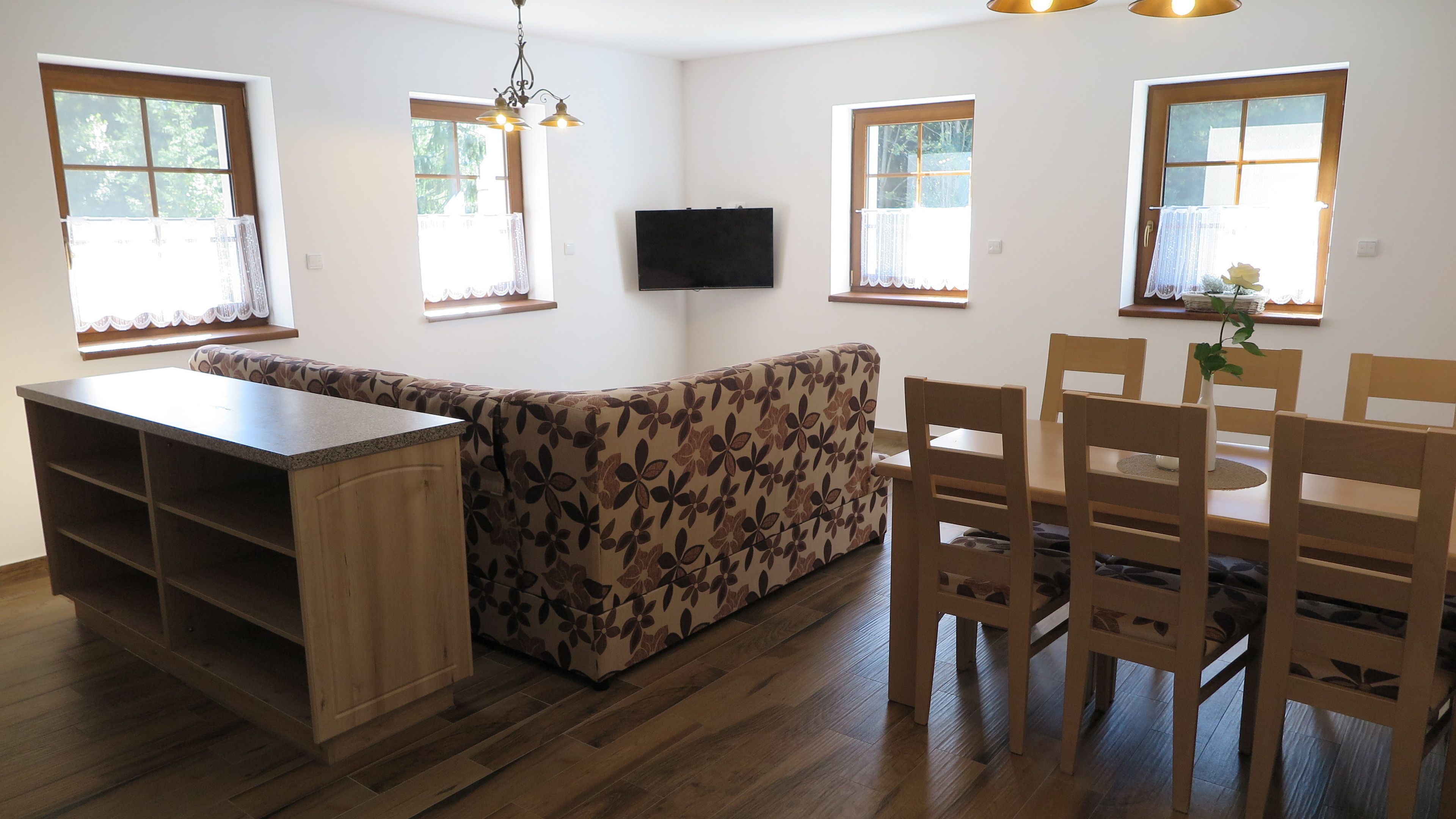 A modern kitchen with a wooden countertop, a built-in bench, and a dining area with wooden chairs and a table.