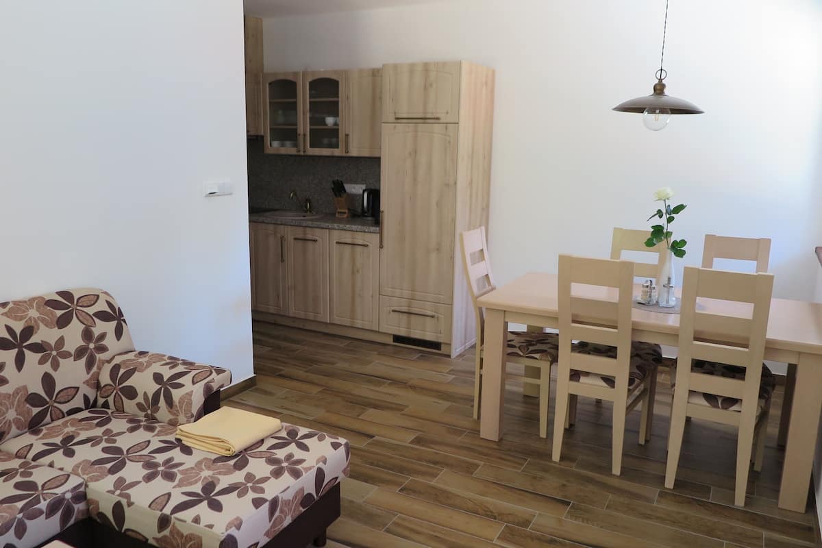 Un espacio habitable compacto con sofá, una mesa de comedor con sillas y una cocina con armarios de madera y una lámpara colgante.