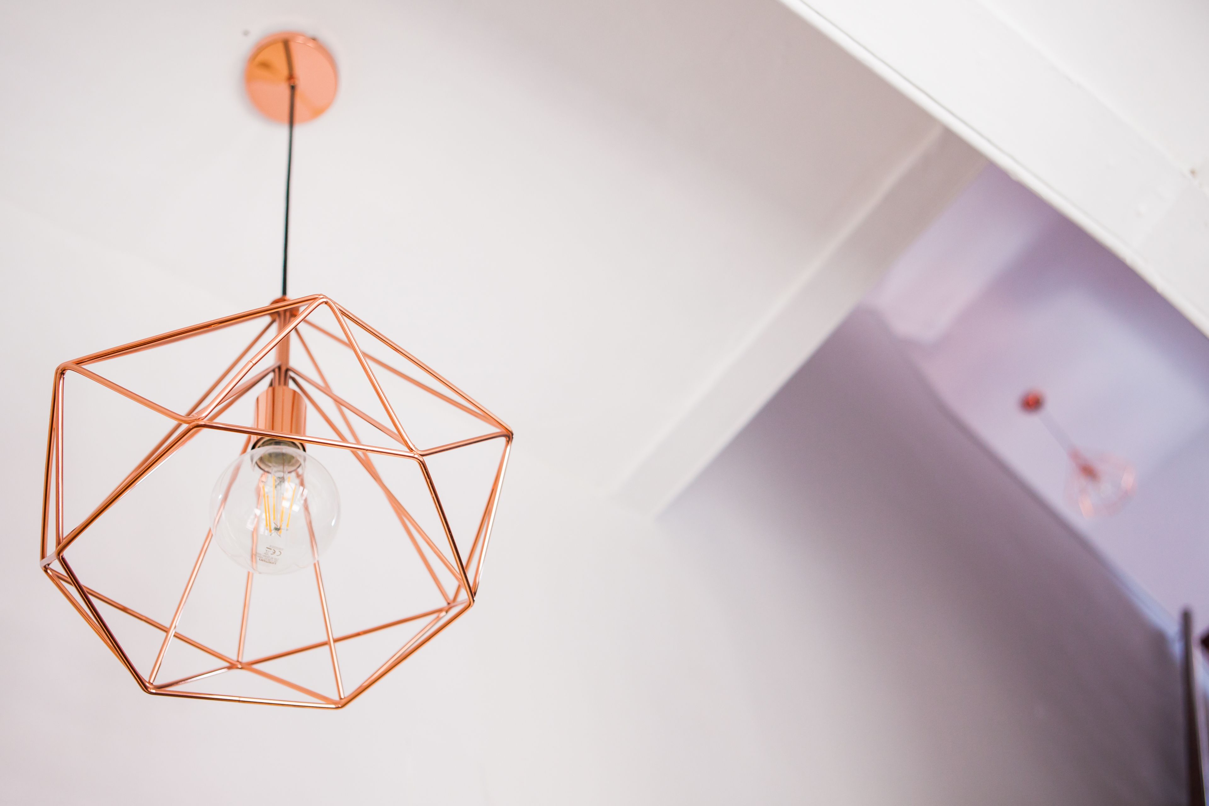 Un luminaire suspendu de forme géométrique, avec une ampoule visible.