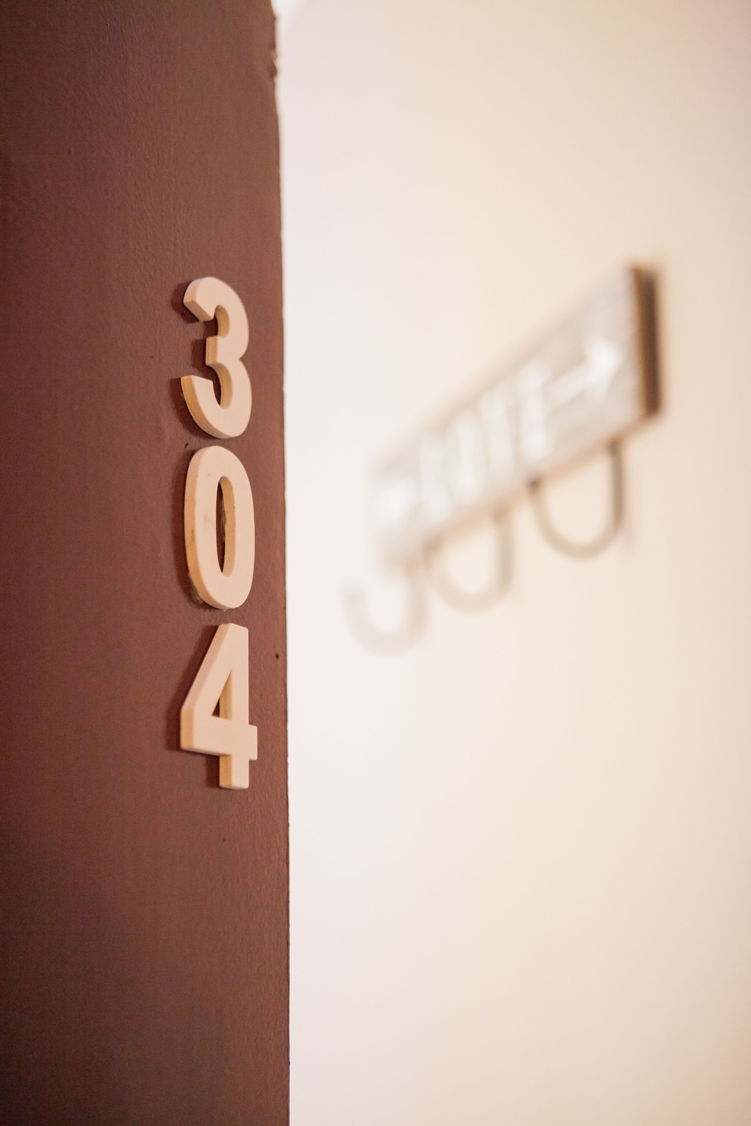 A close-up of a wall with the numbers "304" in a wooden block.