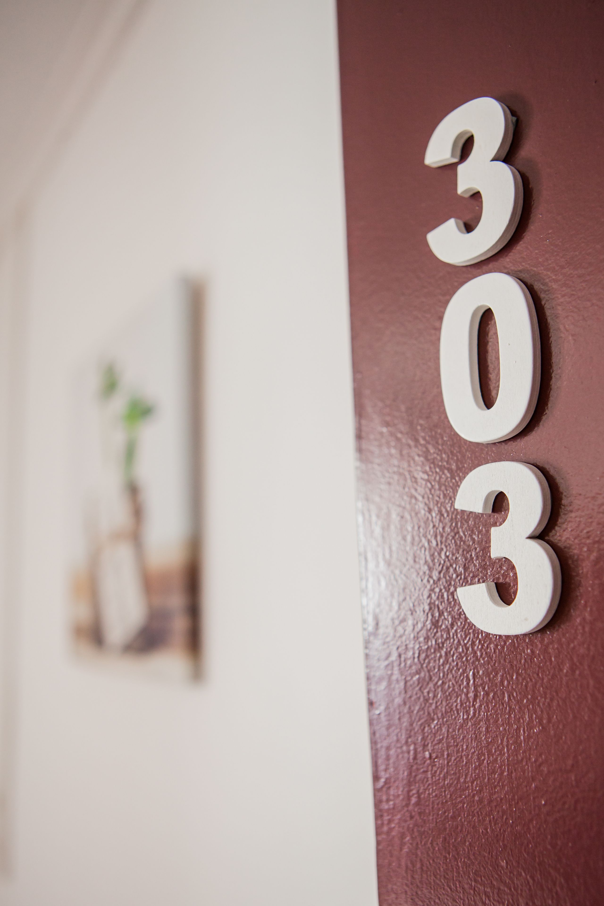 Un dettaglio di un muro con i numeri “303” in bianco.