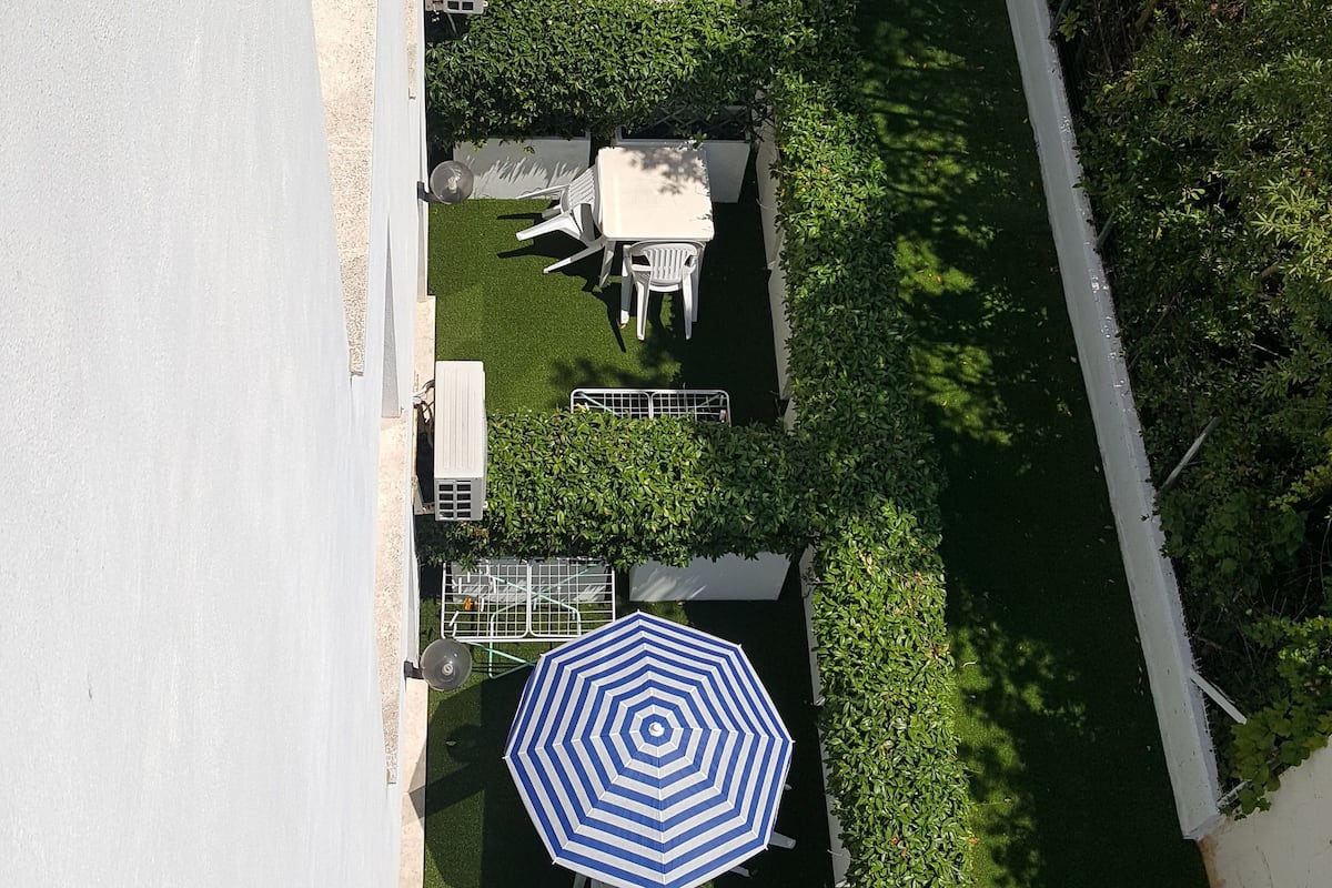 Une vue aérienne d’un quartier résidentiel avec une pelouse bien entretenue, une clôture blanche et une rangée de maisons dont on peut voir les fenêtres et les portes.