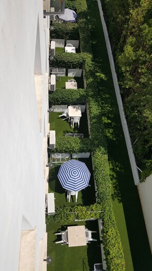 An aerial view of a residential area with a well-maintained lawn, a white fence, and a row of houses with visible windows and doors. - Hotel Le Palme (Sabaudia)
