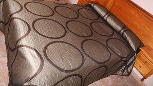 Een bed met een bedovertrek met patroon en een houten hoofdbord.