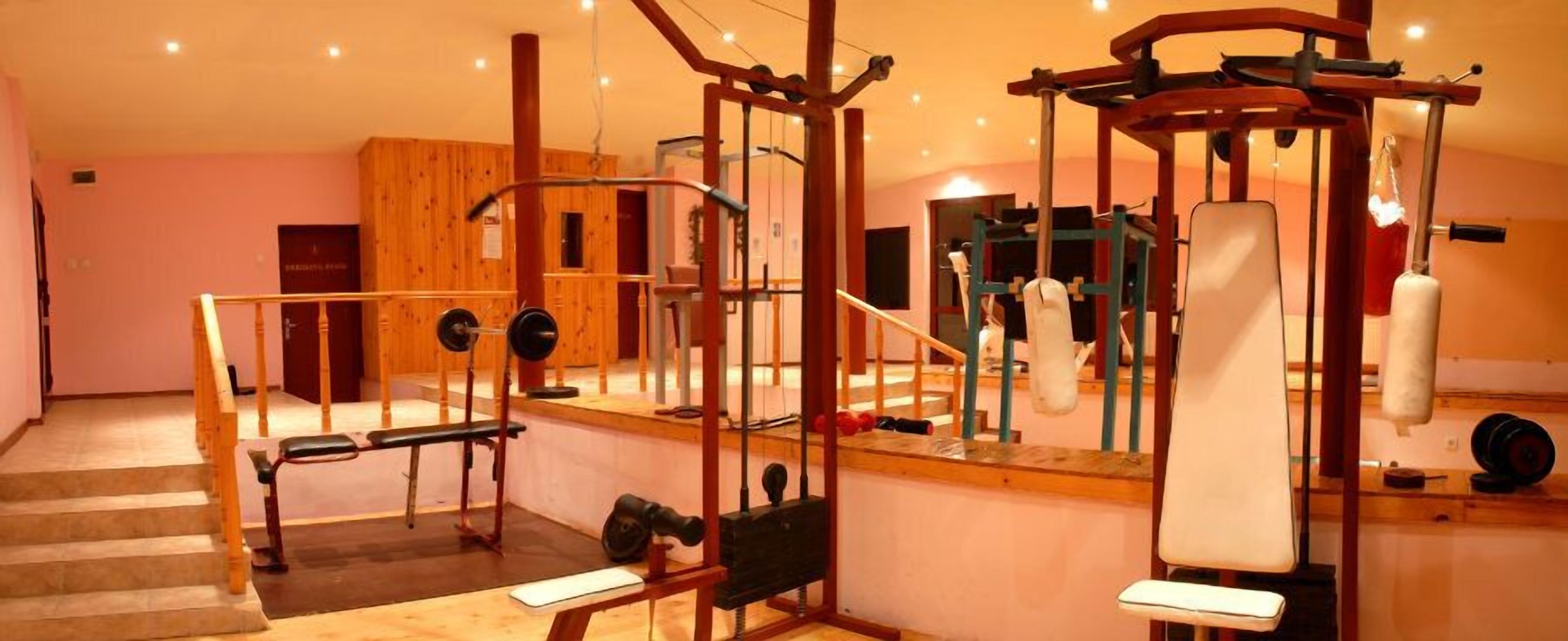 A gym with various exercise equipment, including a bench press, a squat rack, and a cable machine.