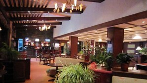 Un vestíbulo de hotel con zona de bar, asientos y plantas en macetas.