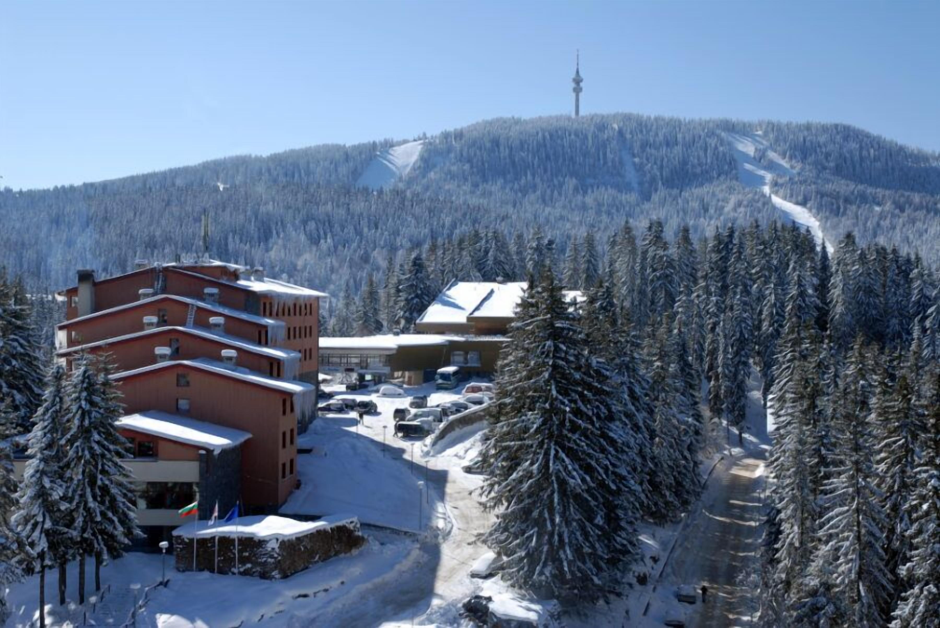 A ski resort with buildings, snow-covered trees, and a ski lift.