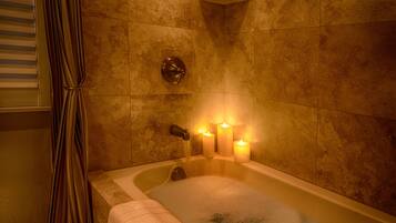 Une baignoire avec trois bougies allumées, une serviette et un rideau de douche.