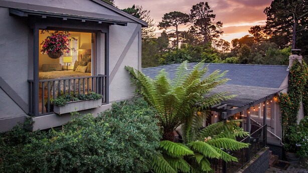 A house with a balcony, a hanging flower basket, and a garden with ferns. - Carmel Country Inn (Carmel)