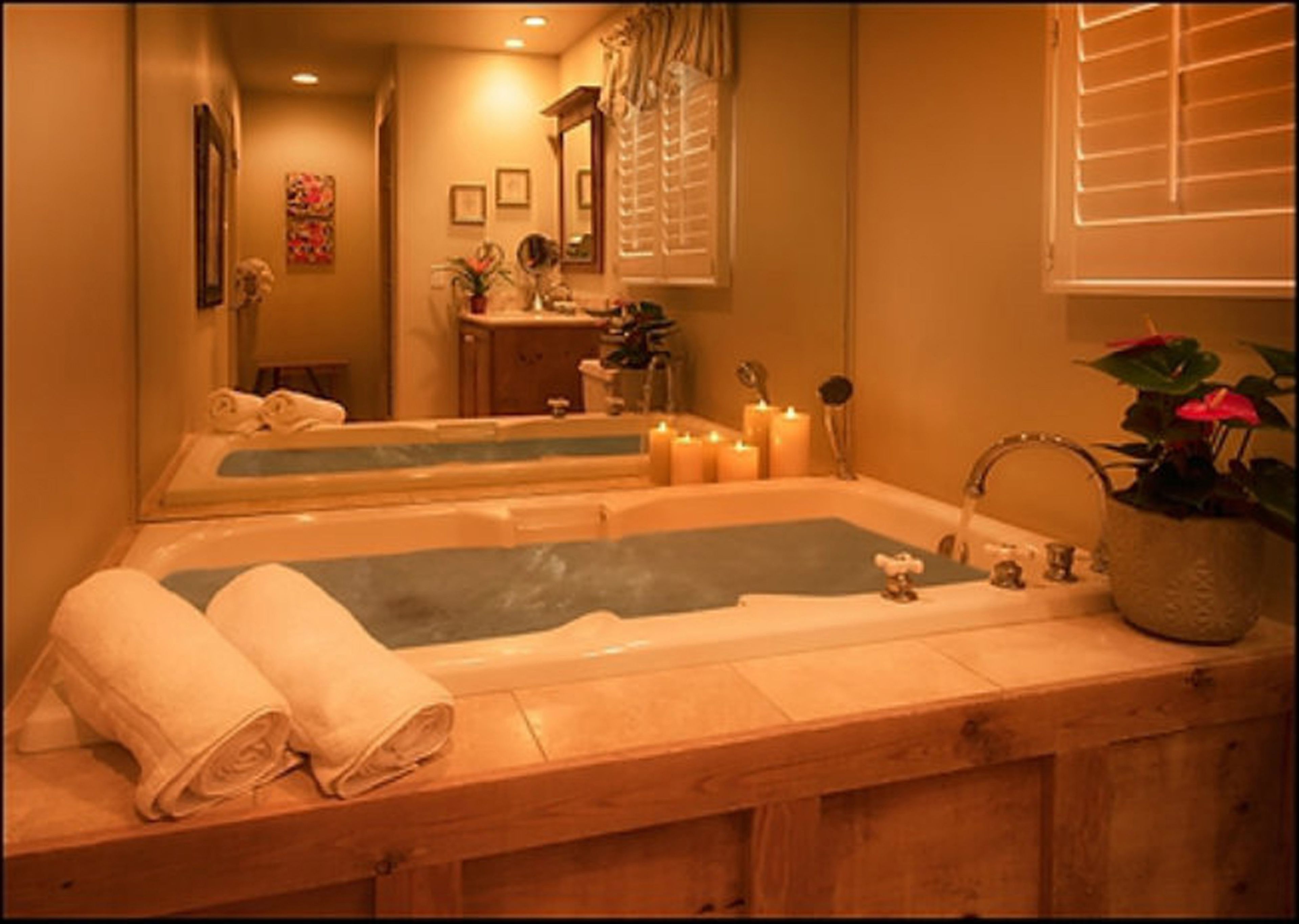 A spa room with a wooden bathtub, towels, candles, and a mirror.