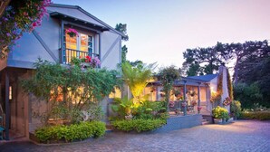 A two-story house with a brick exterior, a balcony with hanging flower baskets, and a paved driveway. - Carmel Country Inn (Carmel)