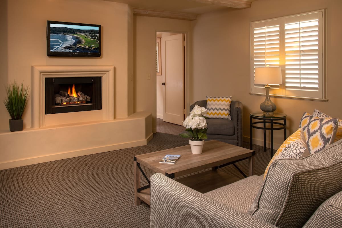 A living room with a fireplace, a television mounted above it, and a sofa with patterned cushions.