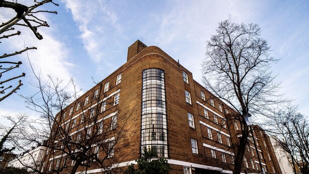 A multi-story brick building with a curved glass facade, surrounded by leafless trees. - Bowden Court - Hostel (London)