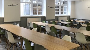A conference room with long tables and chairs, large windows, and motivational wall art. - Bowden Court - Hostel (London)