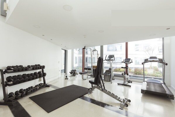 A modern gym with exercise equipment, a treadmill, and dumbbells. - Friendship House - Hostel (London)