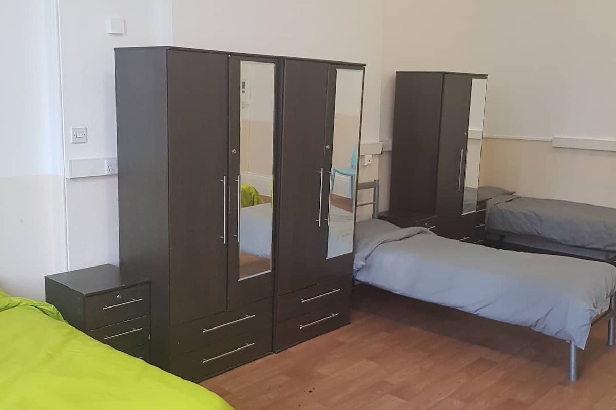 Una habitación con dos camas, un armario y un espejo.