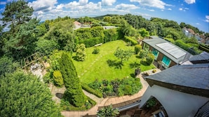 A lush garden with a well-maintained lawn, a wooden pergola, and a variety of shrubs and trees. - Sea View Holiday Flat - Covehurst Bay (Hastings)