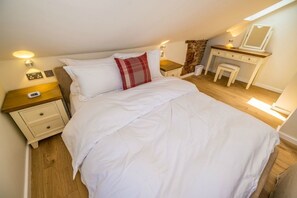 A bedroom with a bed, bedside tables, a dresser, and a mirror.