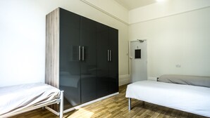 A bedroom with a bed, a wardrobe, and a mirror. - Sandeman-Allen House - Hostel (London)