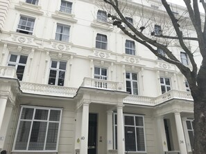 Un bâtiment blanc doté de nombreuses fenêtres et de balcons, et présentant des éléments architecturaux de style classique.