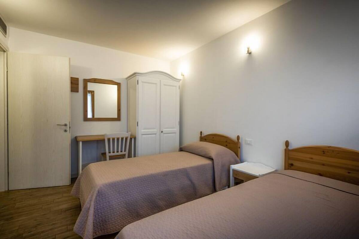 Een slaapkamer met twee bedden, een bureau, een stoel en een kledingkast.