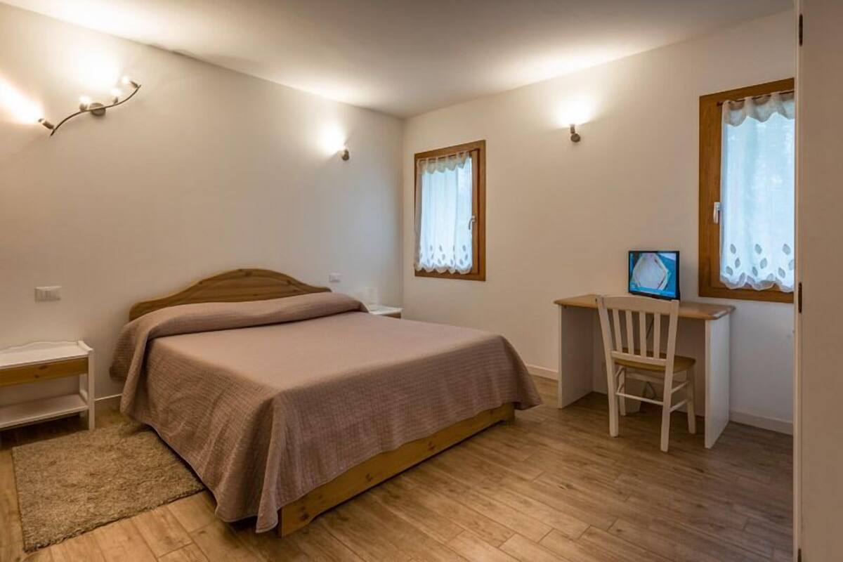 Een slaapkamer met een bed, een bureau en een stoel.