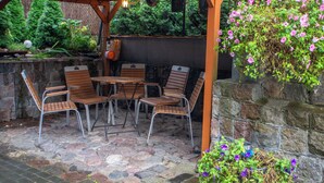 An outdoor patio with stone flooring, wooden chairs, and tables. - Villa Asesor (Gdansk)