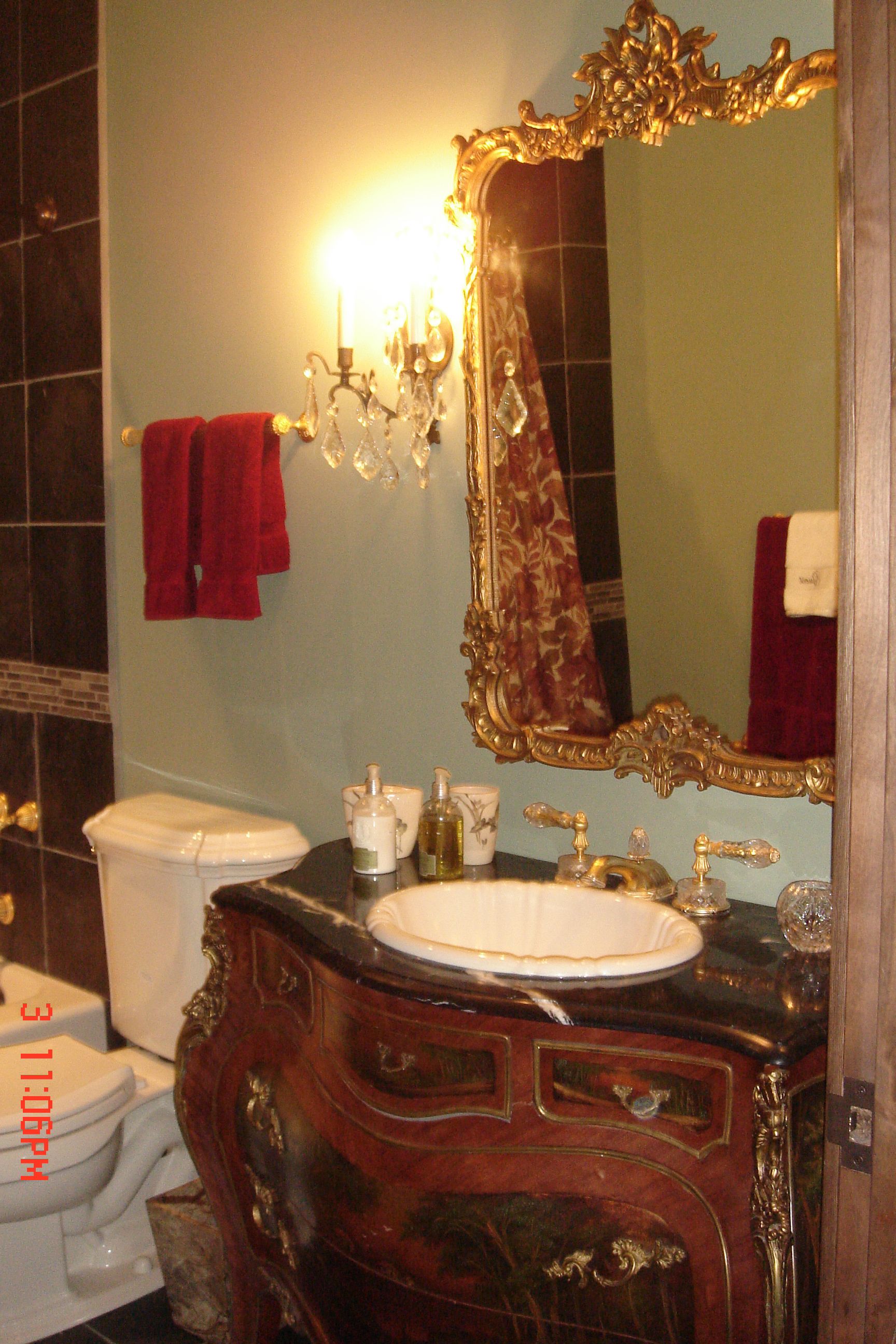 Un bagno con un mobile bagno vintage, uno specchio grande e decorativo e un lavandino bianco.