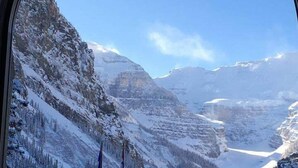 Uma área de refeições com vista para montanhas cobertas de neve através de uma janela.