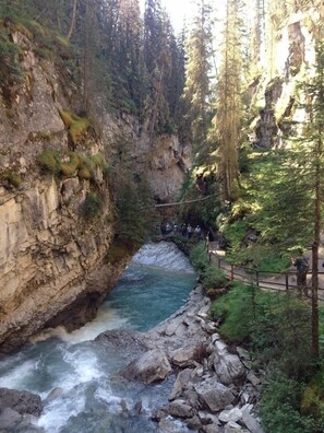 A river flowing through a rocky gorge with a wooden walkway and a railing. - Chateau Elise (Canmore)