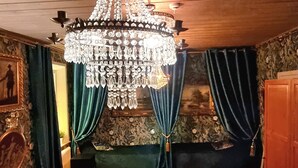 Une pièce dotée d’un grand lustre, d’un canapé en velours vert et d’un tapis à motifs.
