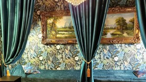 Une pièce avec un grand lit, un banc, un lustre et un tableau au mur.