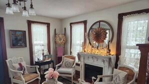 A traditional living room with a fireplace, floral arrangements, and classic furniture. - Applesauce Inn B&B (Bellaire)