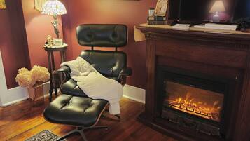 A living room with a fireplace, a television, a leather chair, a patterned rug, and a framed picture on the wall.