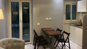 Ein Essbereich mit Tisch und Stühlen, einem Fenster mit Jalousien sowie einer Klimaanlage.