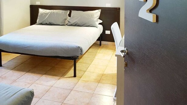 Ein Schlafzimmer mit einem Bett, einem Nachttisch, einem Stuhl und einer Tür mit der Nummer 2.