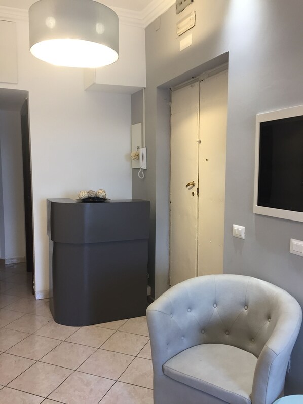 Une salle de bain moderne avec un meuble-lavabo gris, une chaise blanche et un grand miroir.
