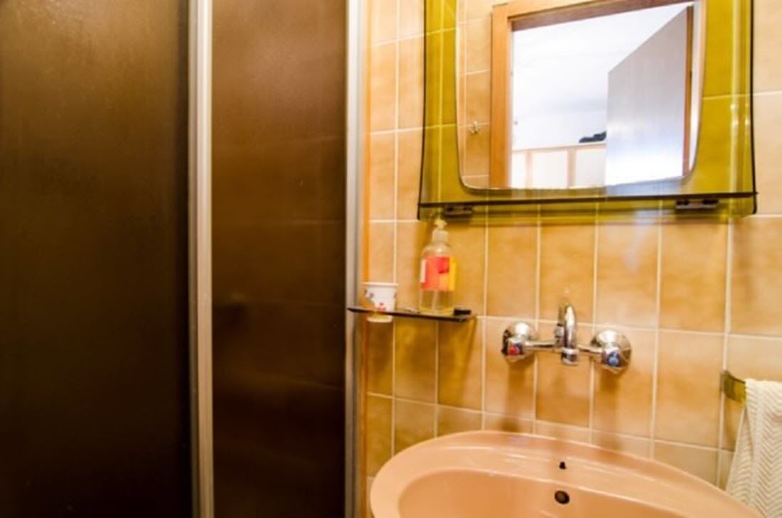 A bathroom with a sink, mirror, and toiletries shelf.