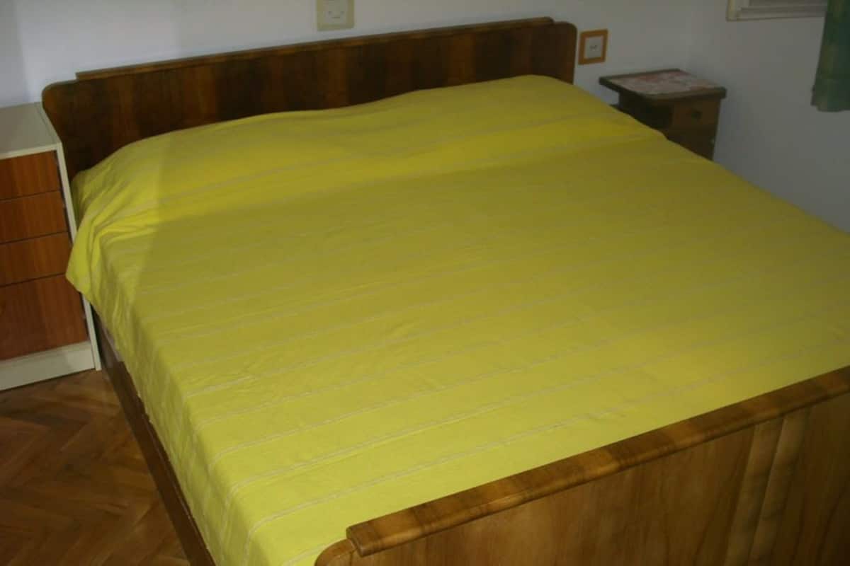 A bed with a wooden headboard and a yellow bedspread.