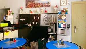 A hotel lobby with a coffee machine, a reception desk, and a wall-mounted painting. - Dolce Vita Rooms & Breakfast (Naples)